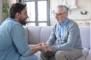 Adult son talking to aging father.