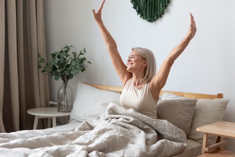 Senior woman stretching on her bed.
