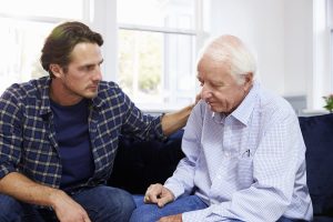 Adult son comforting an aging parent