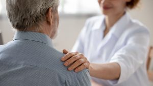 Caregiver touching an older man's shoulder