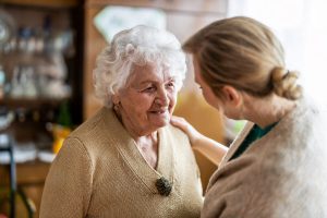 Caregiver putting her hand on an older woman