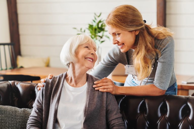 Caregiver smiling to a senior lady in a community
