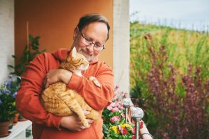 Older adult holding a kitten on his balcony