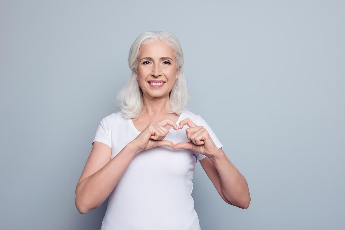 Happy older woman making a heart sign with her hands