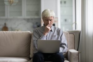 Older man writing his will on a laptop