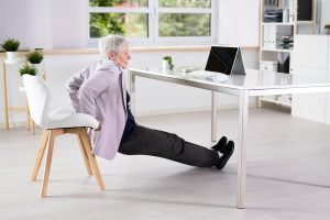 Older woman practicing chair yoga at home