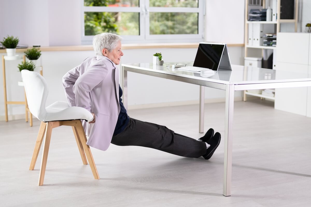 Older woman practicing chair yoga at home